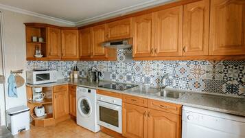 Une cuisine avec des meubles en bois, un lave-linge, un four à micro-ondes et un lave-vaisselle.