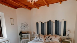 Ein Schlafzimmer mit Holzboden, einem Bett mit floralem Bettbezug, einem Nachttisch mit Lampe und einer Wanddekoration.