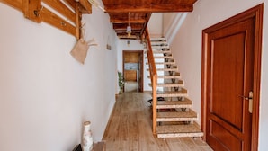 Eine Holztreppe führt zu einem Raum mit einer Holztür und einer Pendelleuchte.
