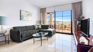 A modern living room with a sofa, coffee table, TV, and a view of the desert through large windows. - 'Gadea 11-2' Apartment with Sea Views, Wi-Fi, and Air Conditioning (Altea)