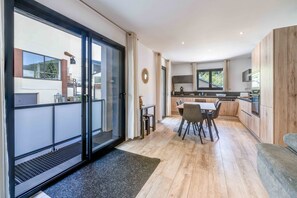 A modern kitchen with a dining area, large sliding glass doors, and a view of the outside. - 'Aux Pieds Des Pistes - Appt A' Apartment with Mountain View, Wi-Fi, and Air Conditioning (Ax-les-Thermes)