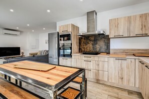Una cocina moderna con armarios de madera, horno integrado y una amplia mesa de madera.