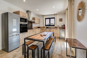 Una cocina moderna con refrigerador de acero inoxidable, armarios de madera, una isla grande y lavavajillas.