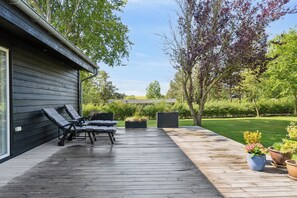 Une terrasse en bois avec des chaises longues, une pergola et des plantes en pot.