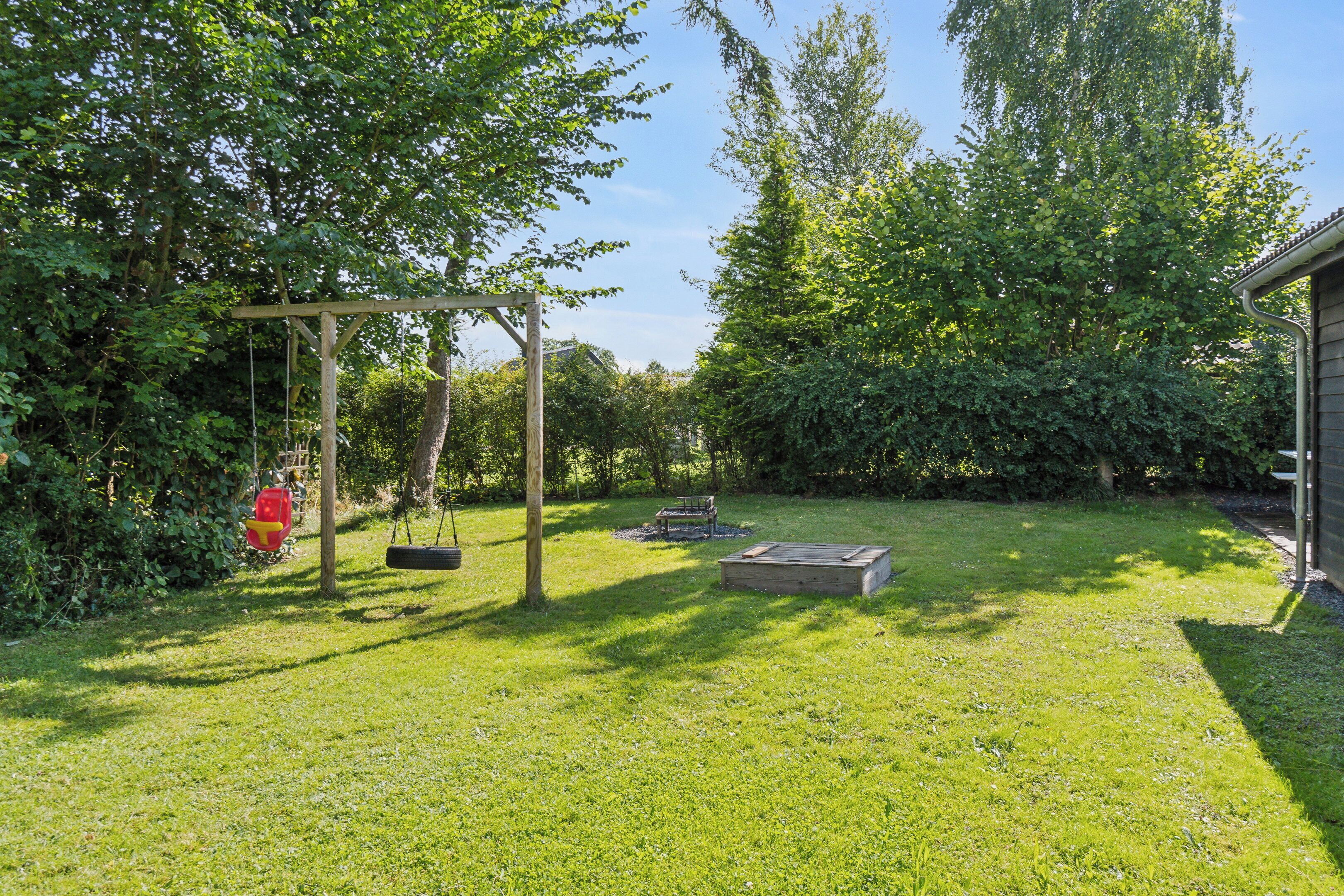Ein Rasen Garten mit Schaukel, Feuerhydrant und einer Holzbank.
