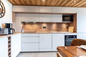A modern kitchen with white cabinets, a wooden countertop, a built-in microwave, and a dishwasher. - Apartment 'Appartement 10' with Mountain View and Balcony (Hauteluce)