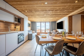 A modern kitchen with a built-in oven and a dining area with a wooden table set for four.