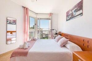 Una habitación de hotel con cama, escritorio, silla y balcón con vistas.