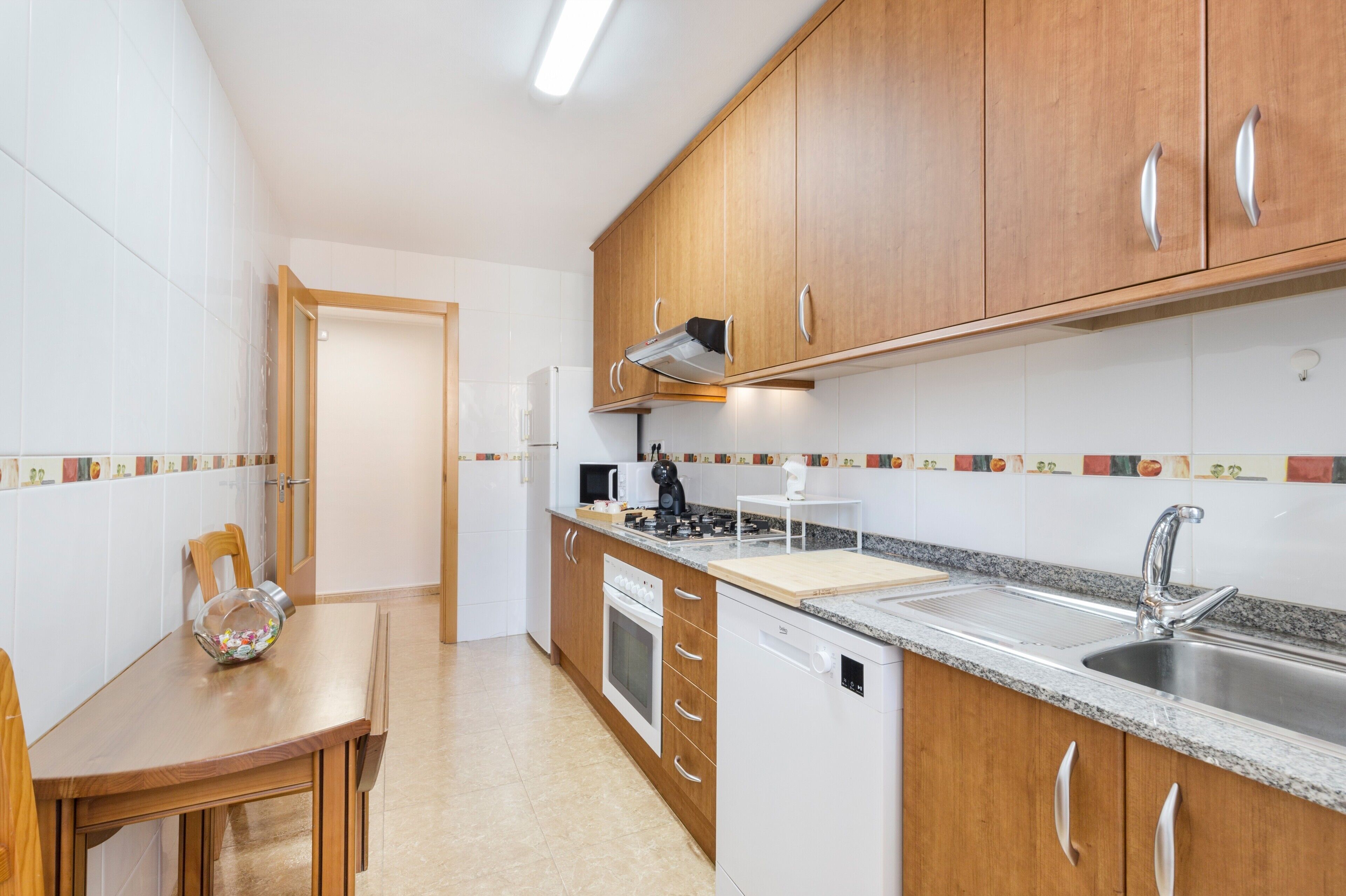 Een moderne keuken met houten kastjes, een roestvrijstalen spoelbak en een eettafel met een glazen schaal.