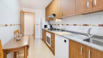 Een moderne keuken met houten kastjes, een roestvrijstalen spoelbak en een eettafel met een glazen schaal.