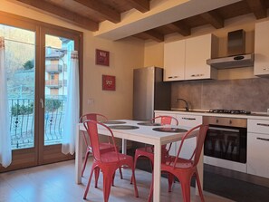 A kitchen with a dining table, chairs, cabinets, and a stove.