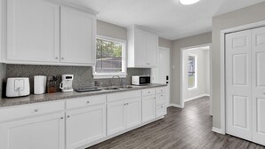 A modern kitchen with white cabinets, granite countertops, and a built-in microwave. - A Gem on 5th St (Tyler)