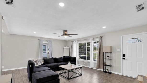 A modern living room with a sectional sofa, a coffee table, and a ceiling fan. - A Gem on 5th St (Tyler)