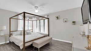 A four-poster bed with a bench, a ceiling fan, and a TV on a stand. - A Gem on 5th St (Tyler)