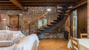 A rustic interior with a stone wall, wooden staircase, and a cozy seating area. - Country House 'El Paraiso Del Yayo' with Mountain View, Private Terrace and Wi-Fi (Cantabria)