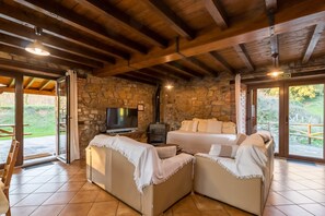 Una habitación acogedora con paredes de piedra, chimenea, televisión y sofá.