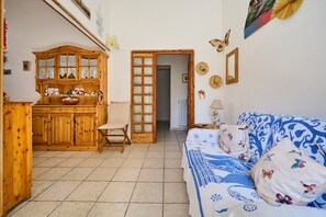 A room with a wooden cabinet, a bed with patterned bedding, a door leading to another room, and wall decorations.