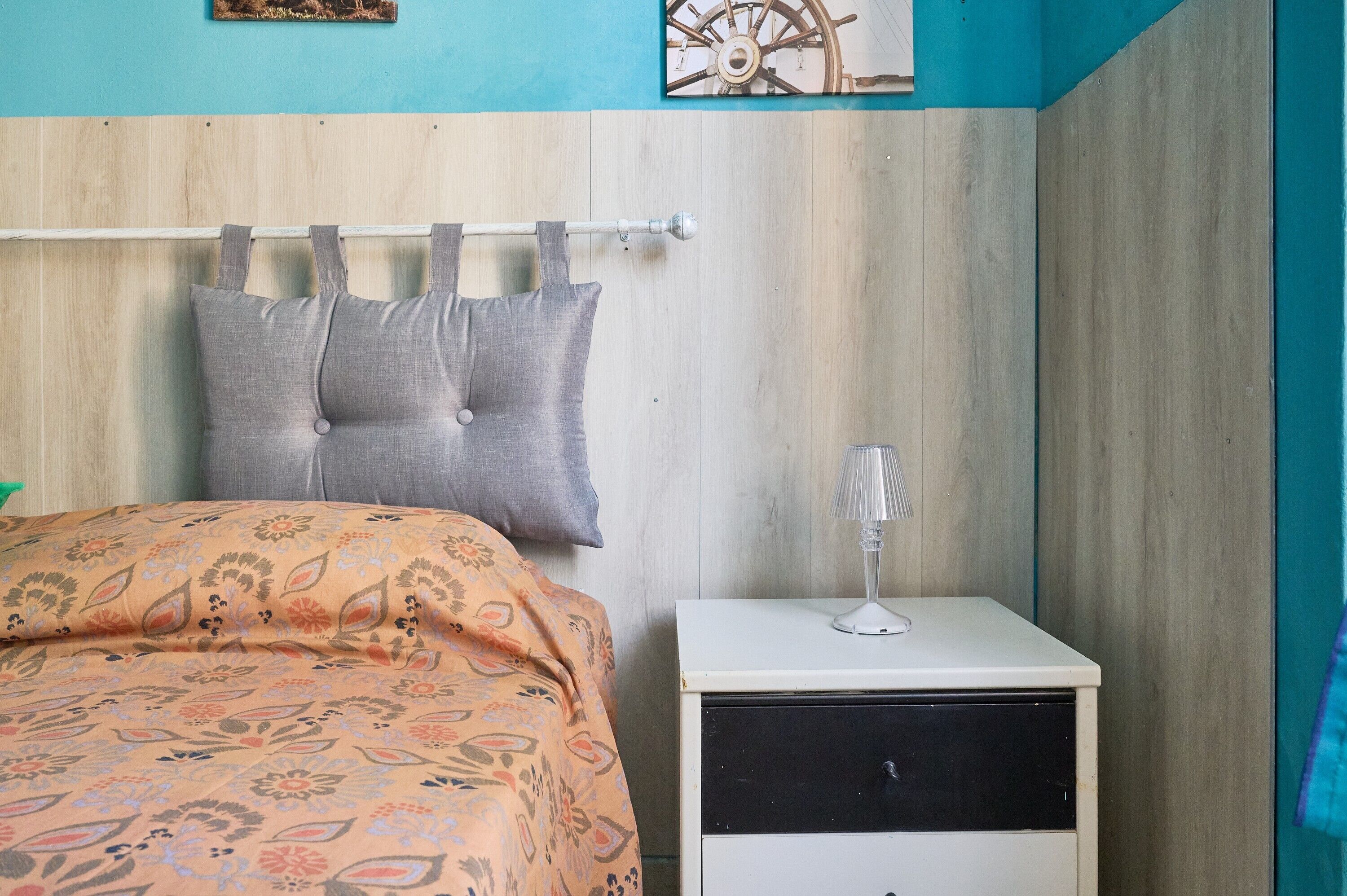Une chambre à coucher comprenant un lit, une table de chevet, une lampe et un mur orné d’un panneau de bois et d’un tableau.