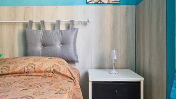 Ein Schlafzimmer mit Bett, Nachttisch, Lampe und einer Wand mit Holzpaneelen und einem Bild.
