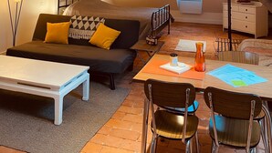 A loft-style room with a sloped ceiling, a bed, a sofa, a dining table with chairs, and a small window. - Studio Apartment 'Hyper-Centre Villa Isabelle' with Mountain View and Wi-Fi (Allevard)