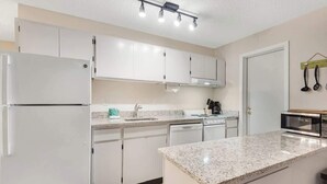 A modern kitchen with white cabinets, a granite countertop, and a built-in oven.