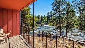 A balcony with a view of a river, trees, and a bridge.