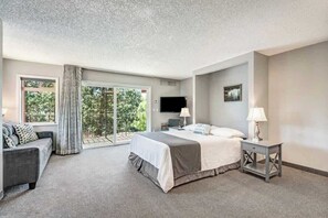 A bedroom with a bed, a TV, a desk, a chair, and a window with curtains. - Riverfront Luxury In Downtown Bend. Pool/Hot Tub. (Bend)