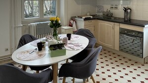 A kitchen with a dining table, chairs, a window, and cabinets.