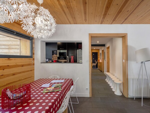 A modern interior with a dining area, a kitchen, and a hallway with toilets.