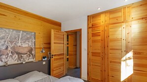 A bedroom with a bed, a wooden wardrobe, a painting of deer, and a hallway. - Modern Family Chalet with Mountain View, Private Terrace and Wi-Fi (Bolquère)