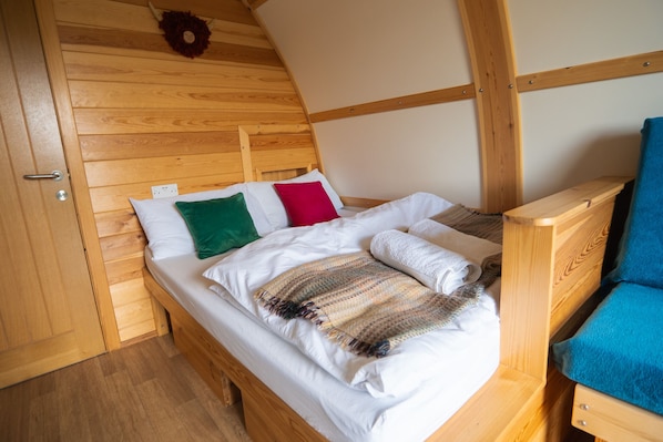 A wooden bunk bed with white bedding and a colorful blanket.