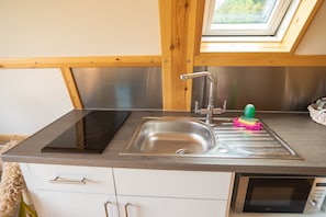 A kitchen with a stainless steel sink, a built-in microwave, and a window above the sink.
