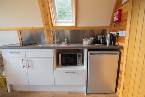 Una cocina compacta equipada con microondas, refrigerador y pileta de acero inoxidable.