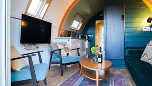 Un espace de vie compact comprenant un téléviseur, un canapé et un petit coin cuisine.