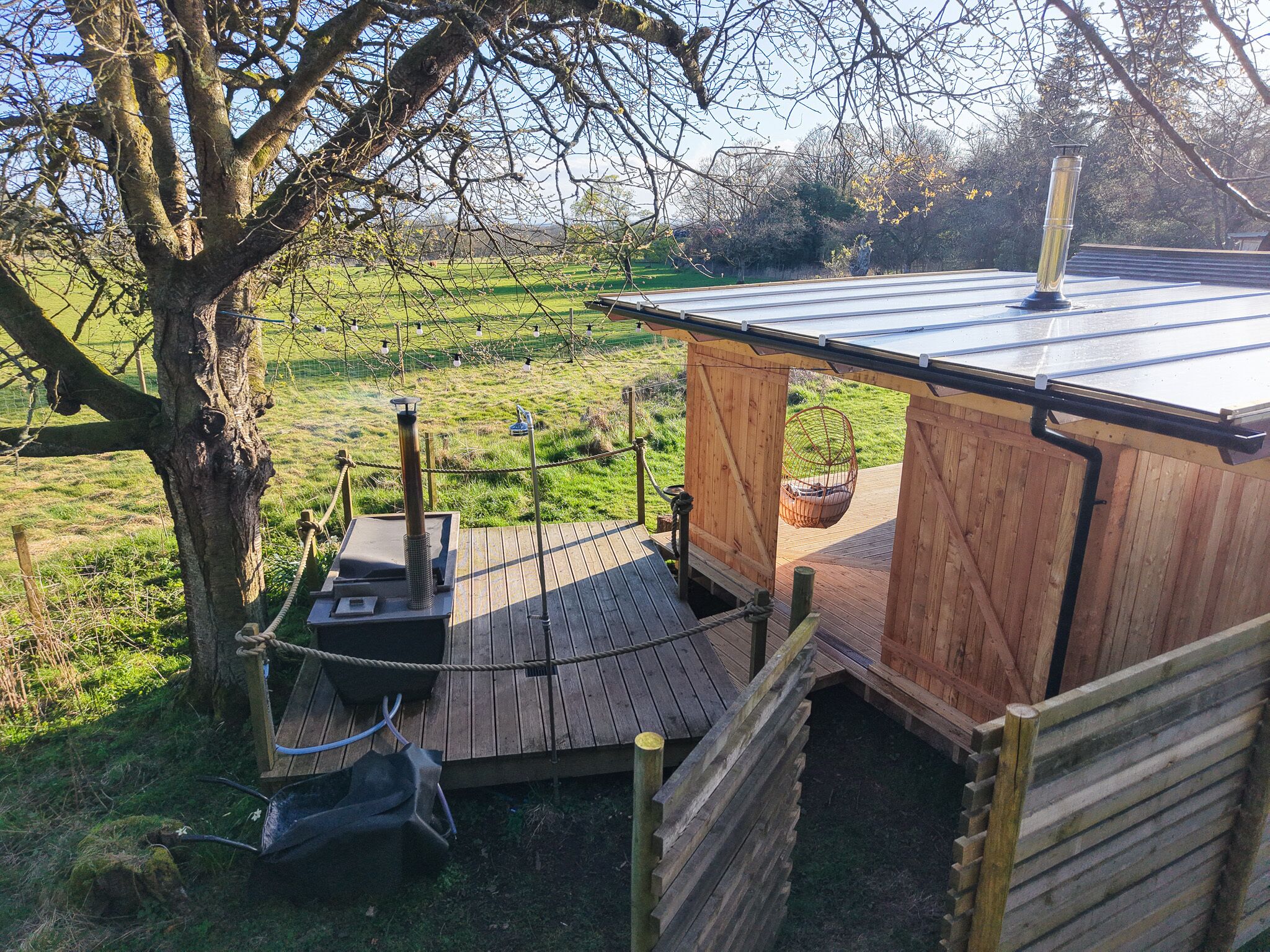 A wooden cabin with a sloped roof, a small deck, and a rope barrier.