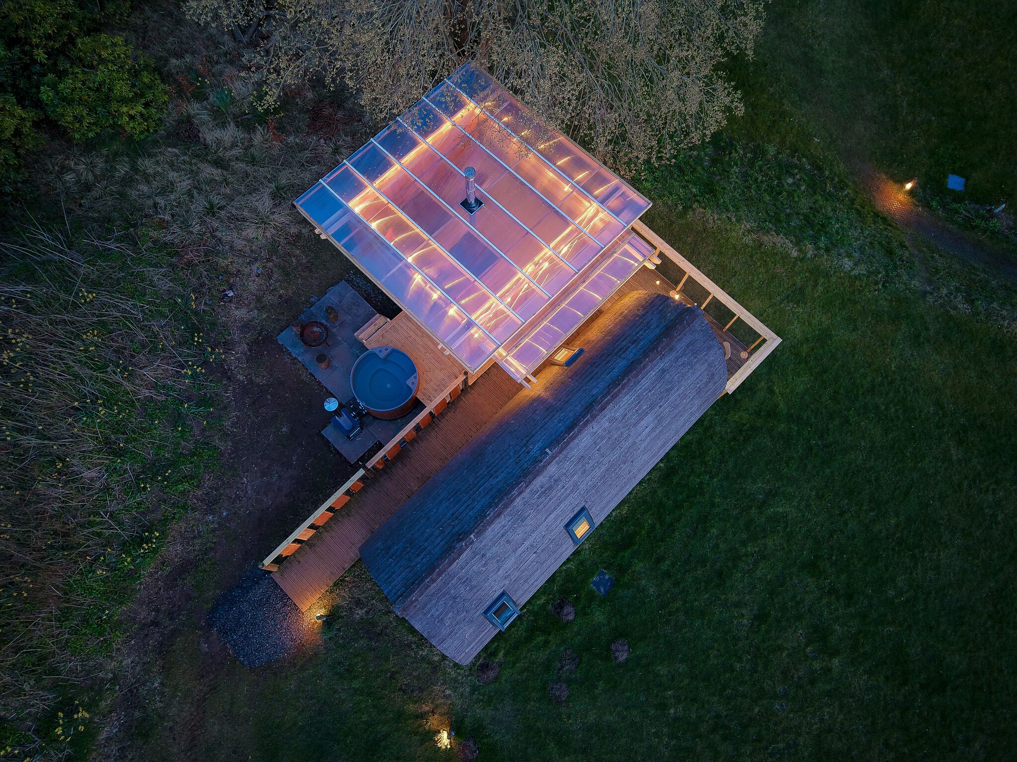 An aerial view of a property with a large deck, a hot tub, and a wooden structure.