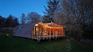 Een houten chalet met schuin dak, balkon en schoorsteen.