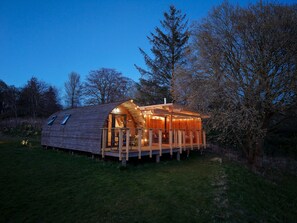 Una cabaña de madera con techo inclinado, balcón y chimenea.