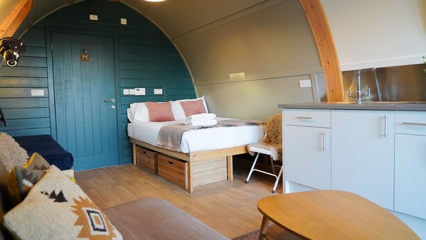 Een gezellige kamer met een bed, een stoel, een tafel en een kitchenette.