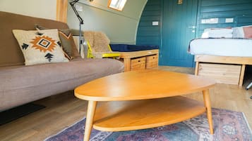 Una habitación acogedora con sofá, una mesita de madera, cama y una silla.