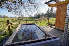 A wooden deck with a rope barrier, a wooden structure, and a clear view of a grassy field. - Cosy, Rural and Ensuite Glamping Cabin. (Leven)