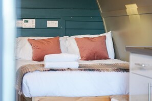 A bed with white and pink pillows, a folded white towel, and a blanket. - Cosy, Rural and Ensuite Glamping Cabin. (Leven)