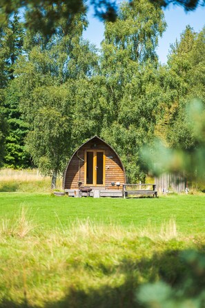 A wooden cabin with a curved roof, a porch, and a door labeled "Lodge." - Cosy, Rural and Ensuite Glamping Cabin. (Leven)