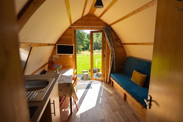 Un interior acogedor con kitchenette, un sofá azul y un ventanal con vistas al exterior.