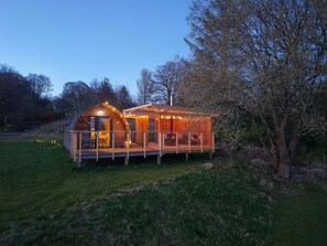 Une cabane en bois avec une terrasse, une cheminée et des guirlandes lumineuses.