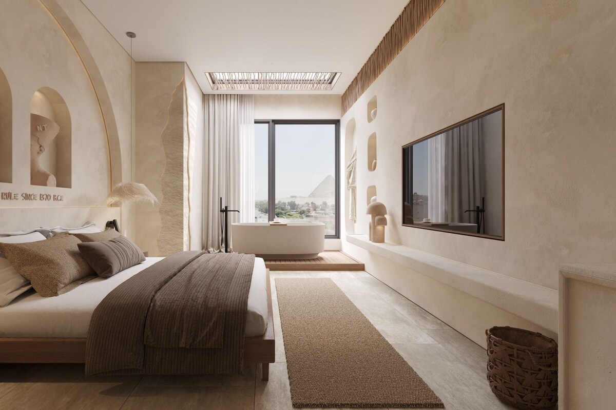 A modern bedroom with a large bed, a bathtub, and a TV on the wall.