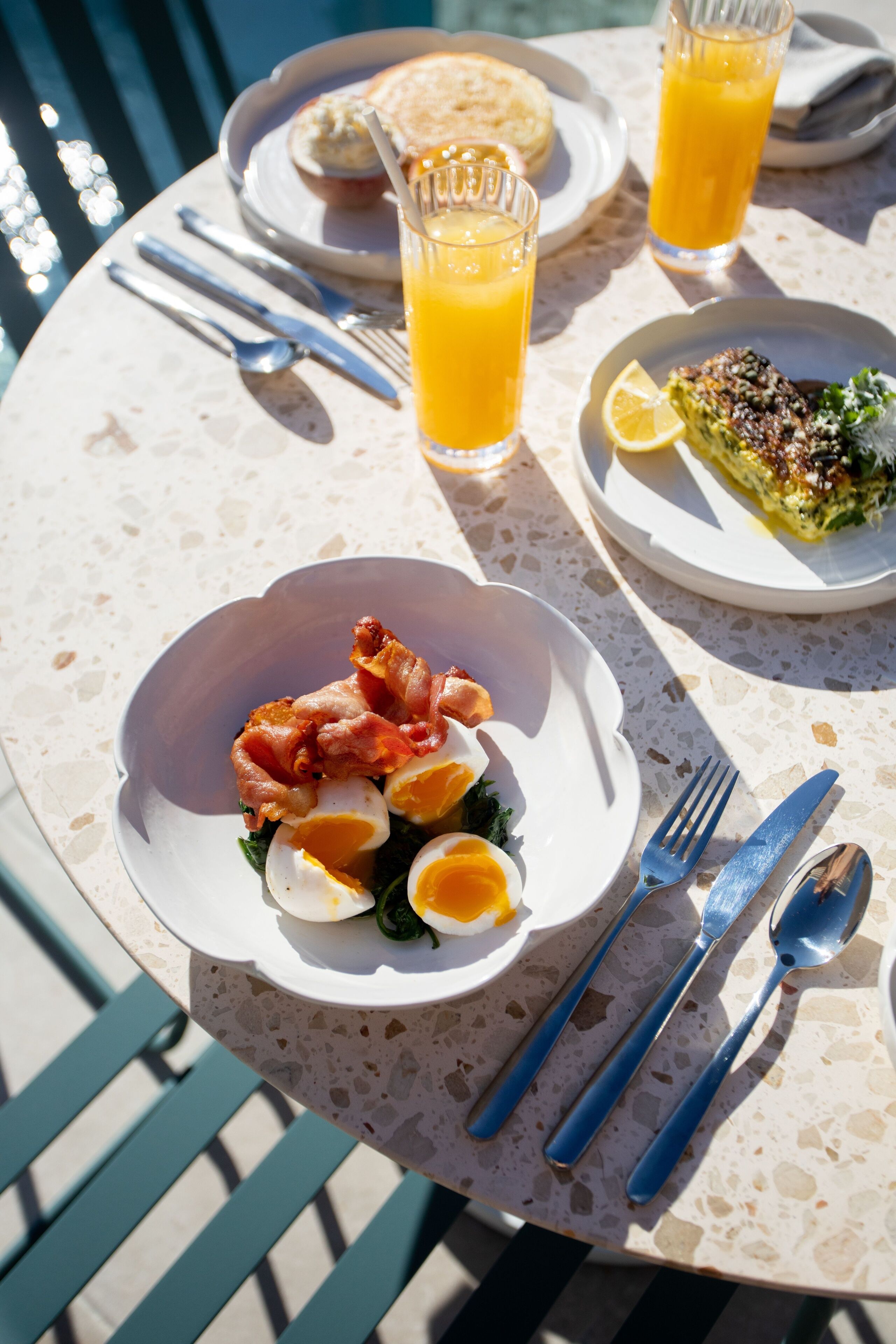 Une table avec des aliments pour le petit-déjeuner, notamment des œufs, du bacon, des toasts et un verre de jus d’orange.