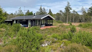 A cabin with a covered porch, surrounded by dense forest. - Unique location on a large sunny natural plot (Ålbæk)