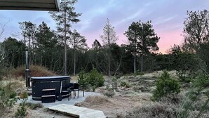 A hot tub with a wooden deck leading to it, surrounded by trees and a natural landscape. - Unique location on a large sunny natural plot (Ålbæk)