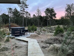 Un bain à remous doté d’une terrasse en bois qui y mène, entouré d’arbres et d’un paysage naturel.